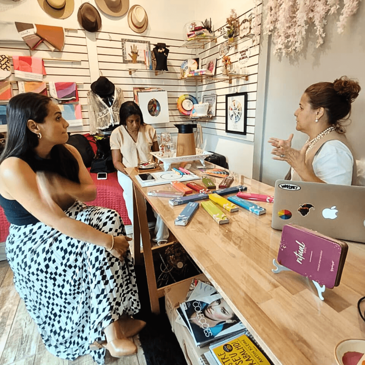 Várias mulheres sentadas ao redor de uma mesa longa, participando de uma reunião ou atividade.