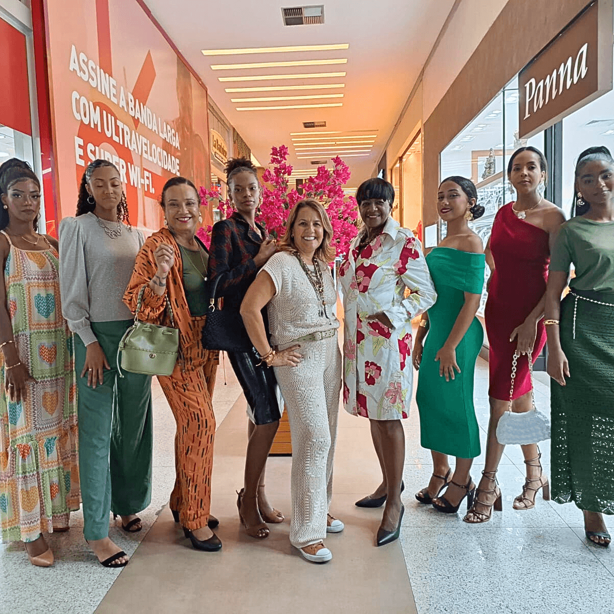 Grupo de mulheres diversas em pé, posando para uma foto em um corredor.
