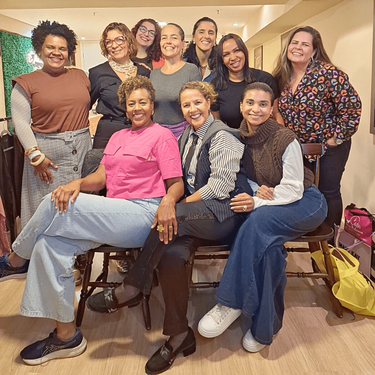 Grupo de mulheres sentadas em cadeiras, posando para uma foto.